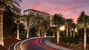 A hotel with a modern design, featuring a prominent sign and palm trees. - Sheraton Universal Hotel (Universal City)