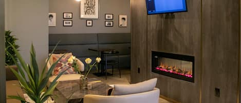 A modern living room with a fireplace, a mounted TV, and framed artwork on the wall.