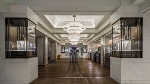 A hotel lobby with a central chandelier, marble flooring, and glass-fronted reception desks. - Sheraton Universal Hotel (Universal City)