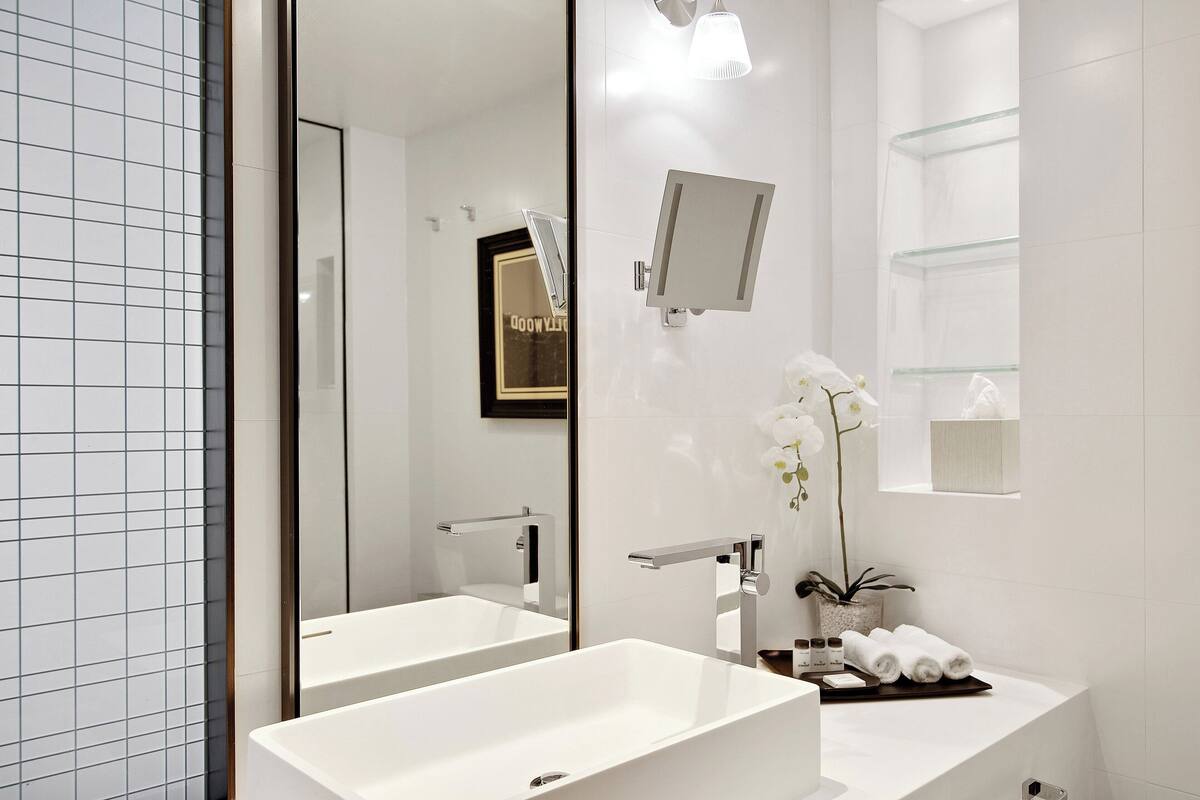 A modern bathroom with two sinks, a large mirror, and a glass shower enclosure.