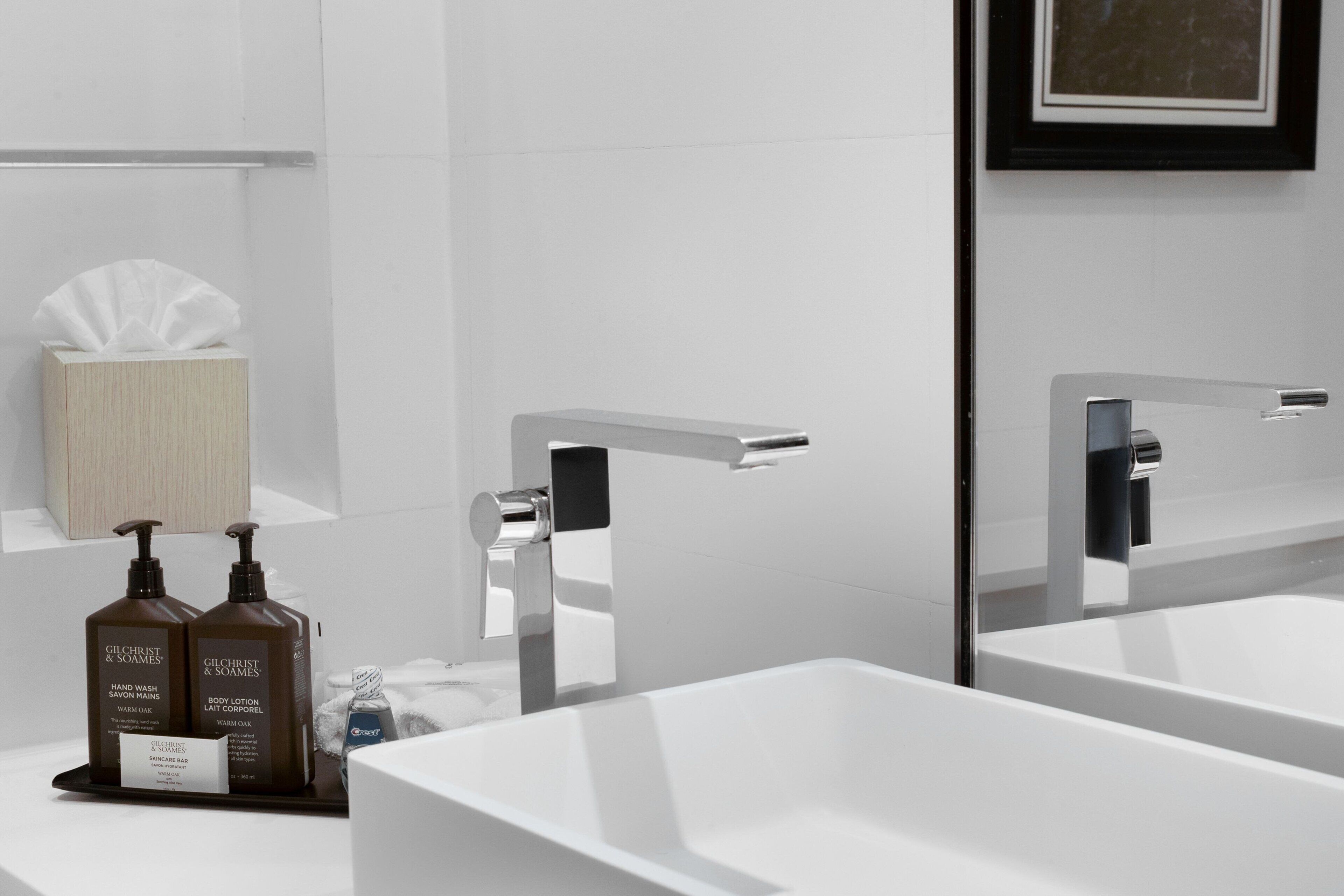 A modern bathroom with two sinks, a large mirror, and toiletries on the counter.