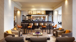 A modern bar area with a bar counter, stools, and a variety of bottles. - Sheraton Universal Hotel (Universal City)