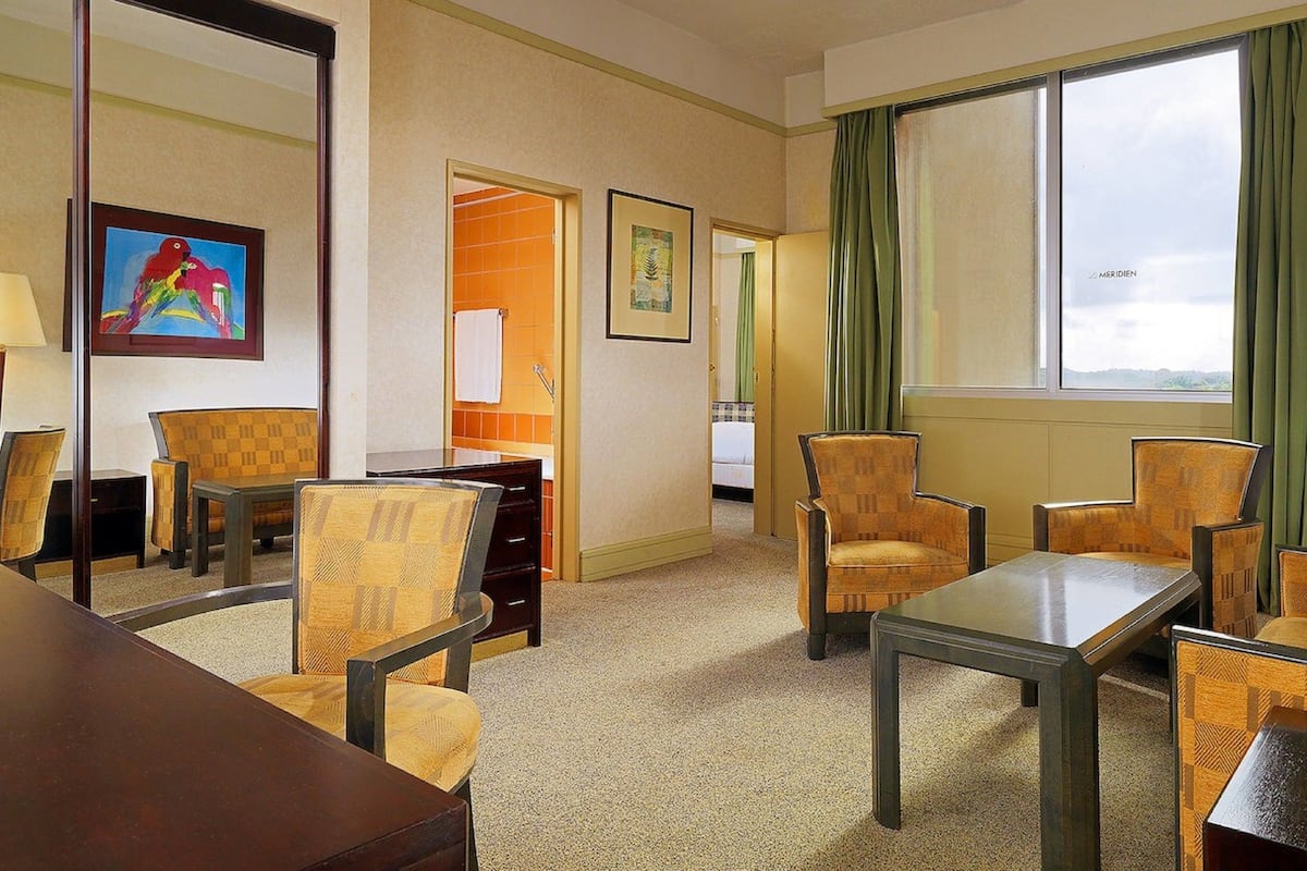 A hotel room with a dining area, a bed, and a view of the outdoors.