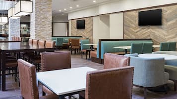 A restaurant with booths and tables, a bar area, and a television mounted on the wall.