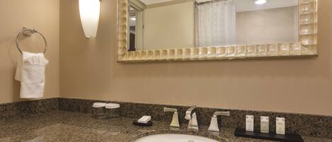 Ein Badezimmer mit einer Granitplatte, einem weißen Waschbecken, einem Spiegel und einem Handtuchhalter.