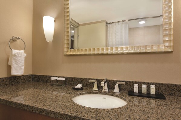 A bathroom with a granite countertop, a white sink, a mirror, and a towel rack. - Embassy Suites Hotel Denver Tech Center (Centennial)