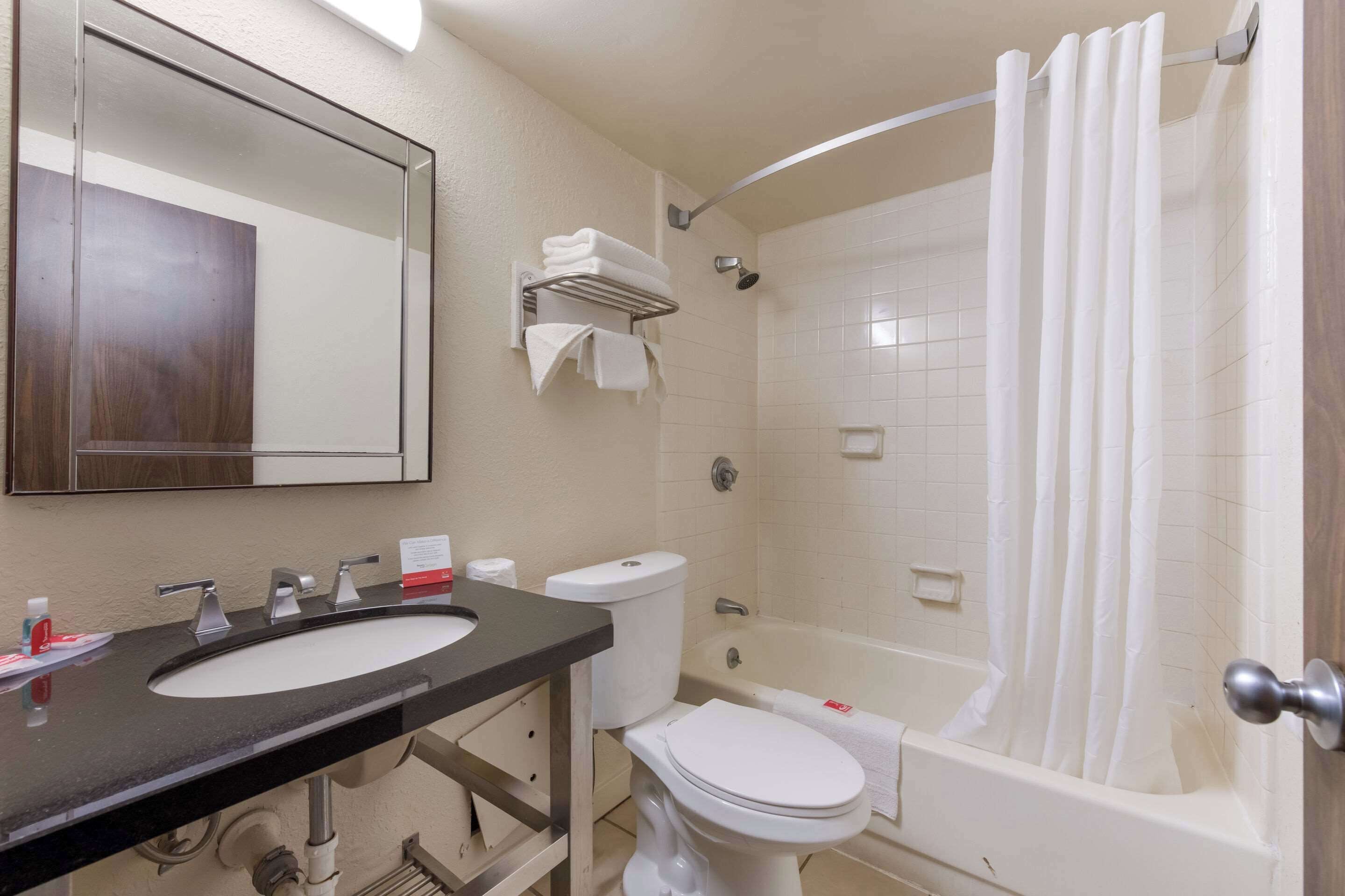 A bathroom with a black sink, white toilet, and a bathtub with a shower curtain.