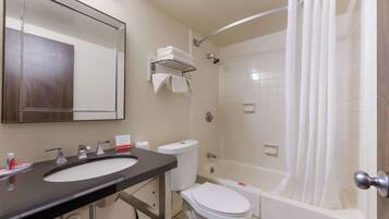 A bathroom with a black sink, white toilet, and a bathtub with a shower curtain.