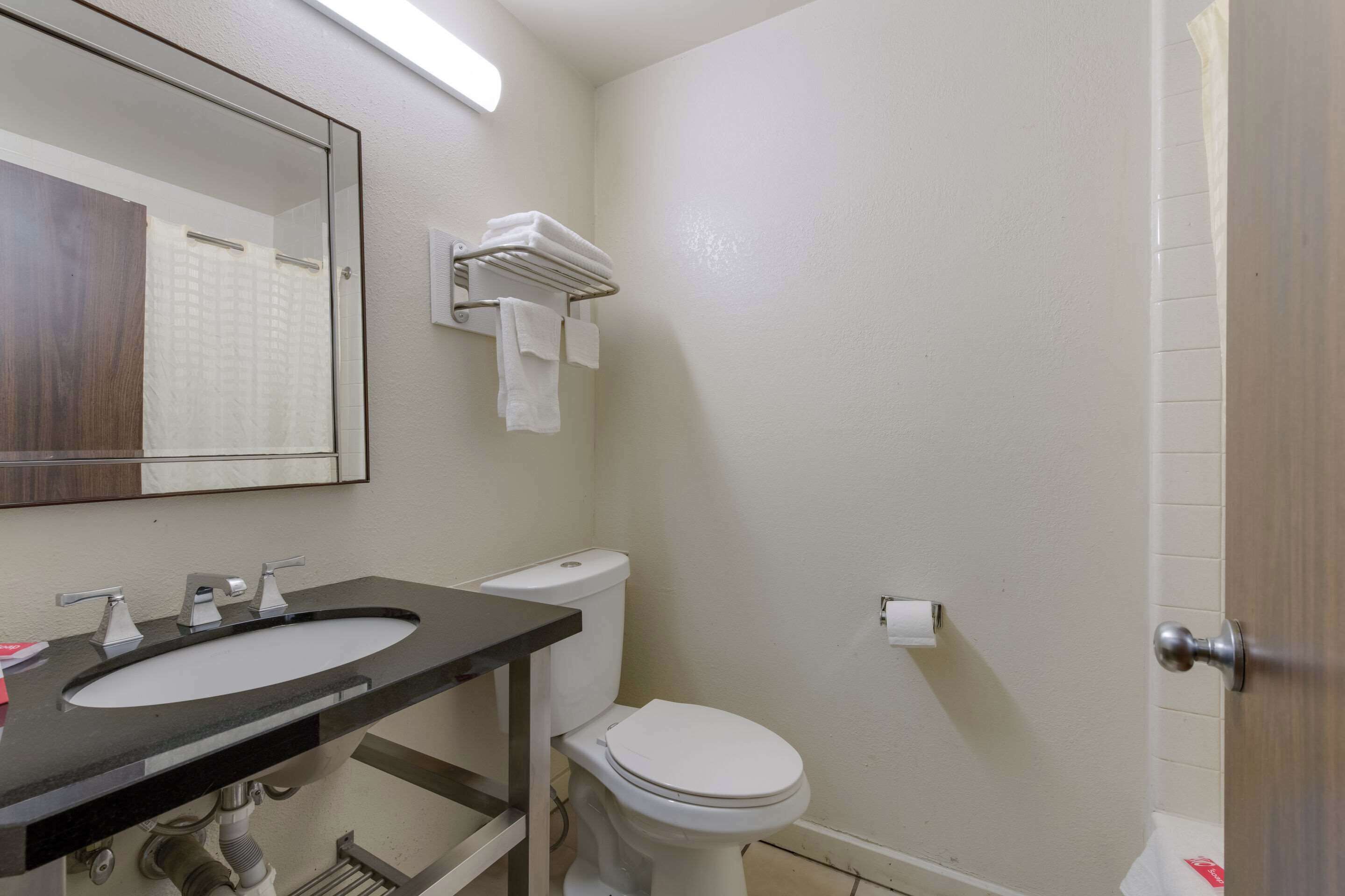 A bathroom with a sink, mirror, toilet, and towel rack.