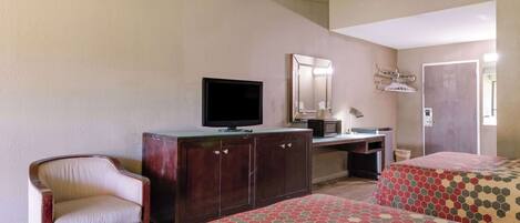 A hotel room with two beds, a desk, a chair, a television, and a mirror.
