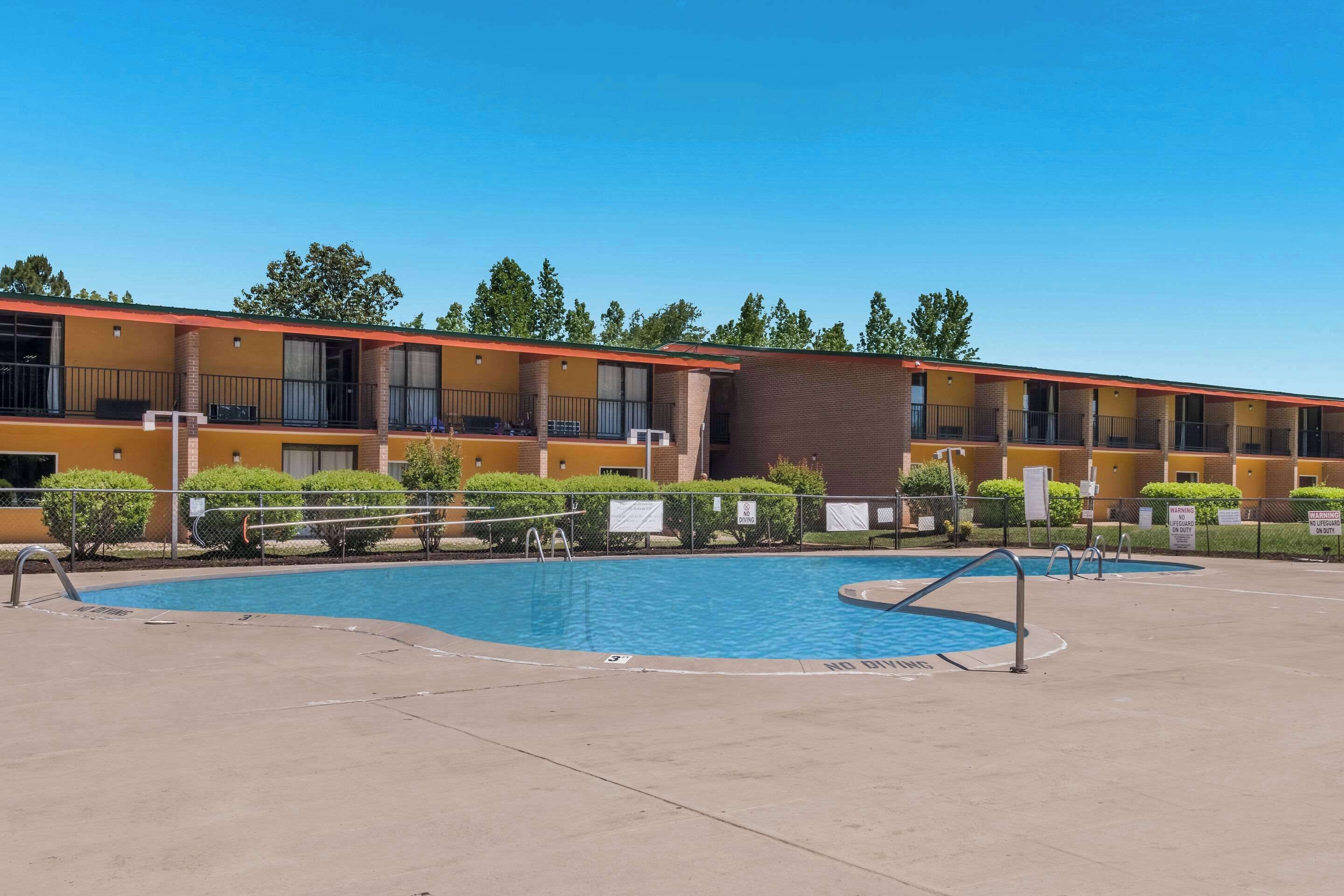 A hotel with a swimming pool, outdoor seating, and a fenced area.