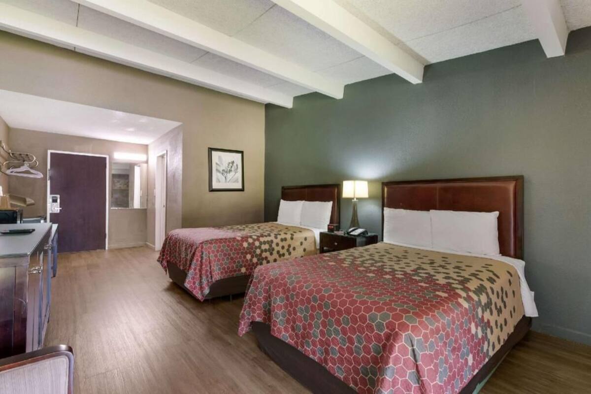 A hotel room with two beds, a desk, and a chair.