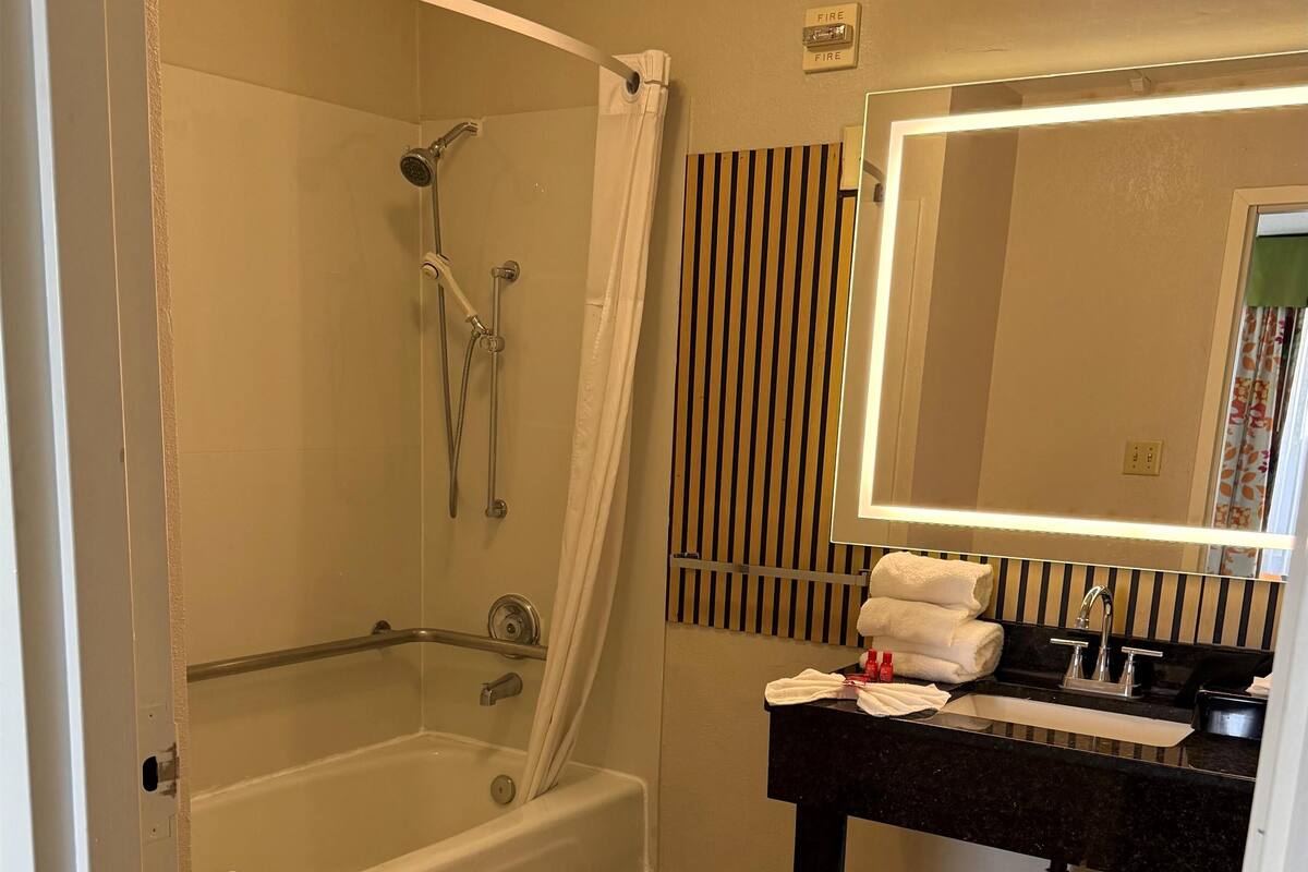A bathroom with a bathtub, a shower, a vanity with a mirror, and a towel rack.