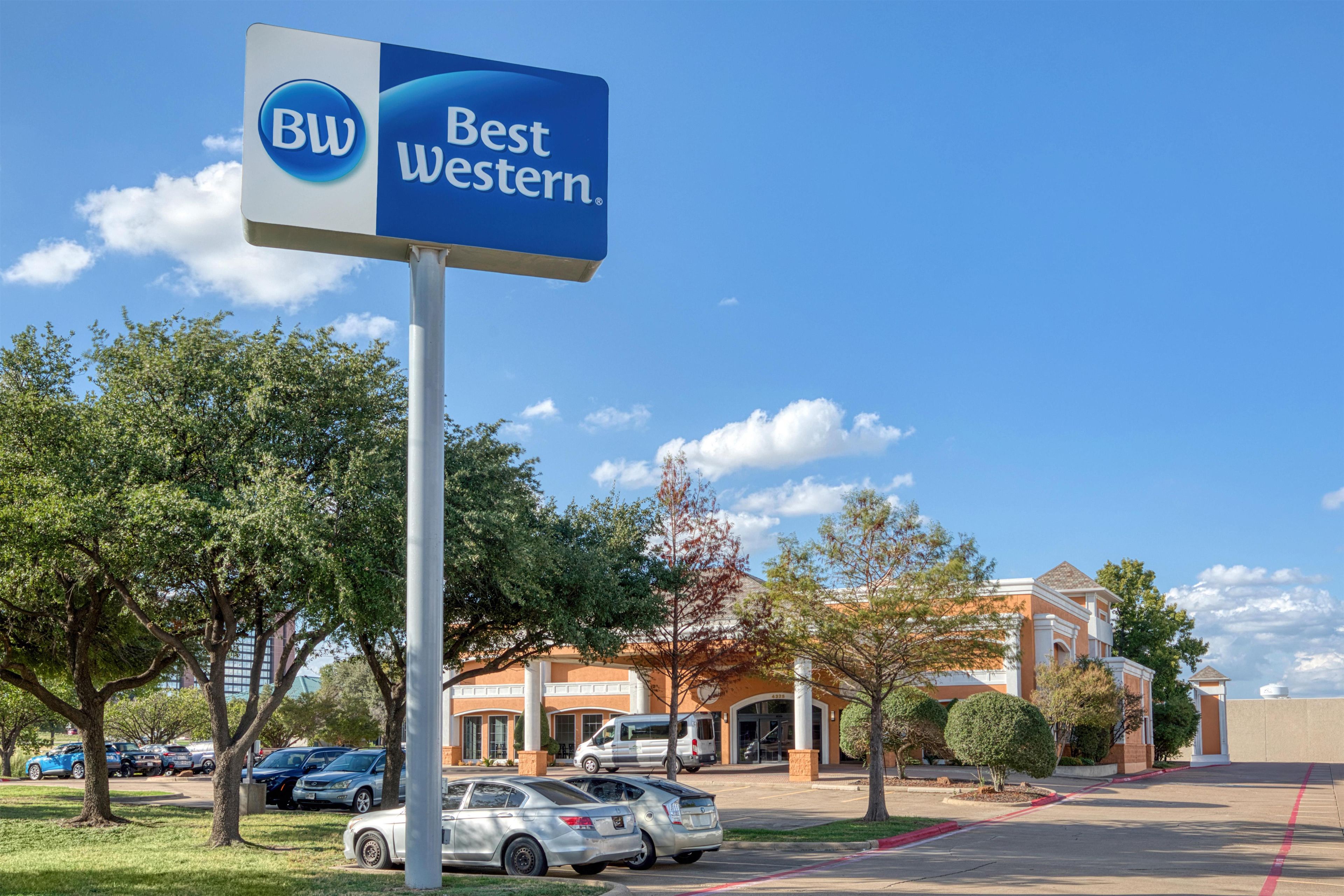 A Best Western sign with a parking lot and buildings in the background.
