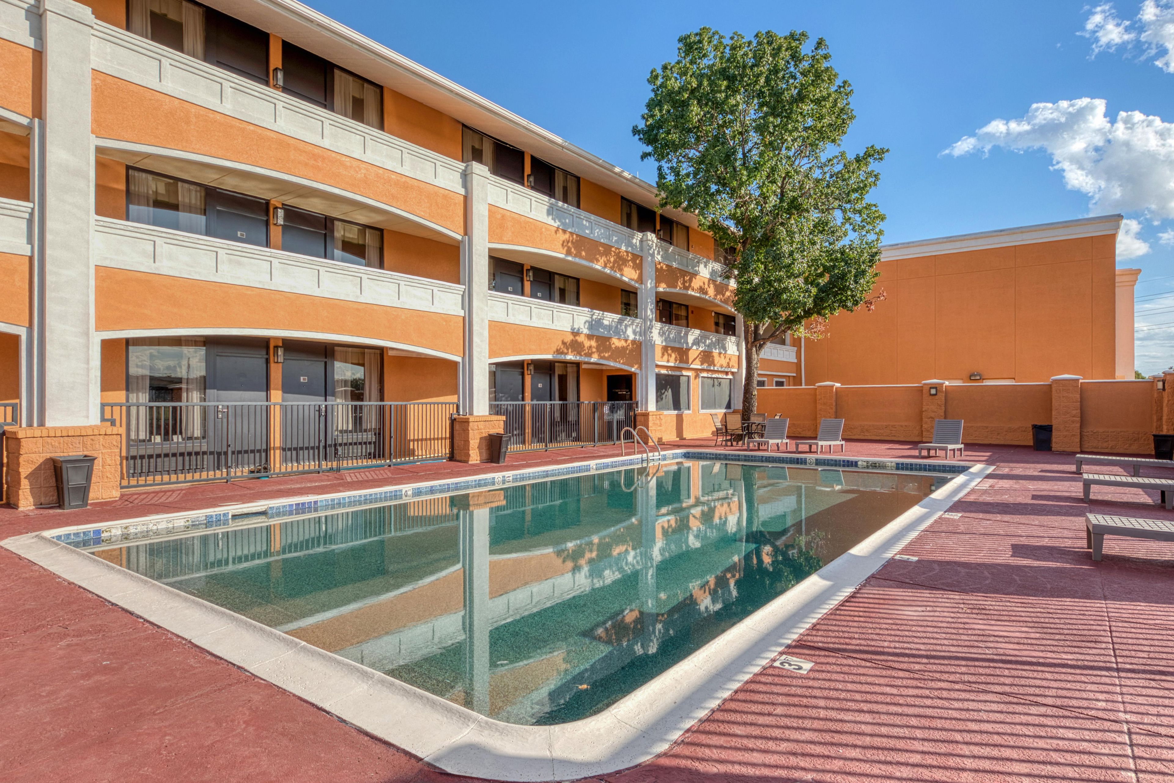 Hotel amb piscina, seients a l'aire lliure i un edifici de diversos pisos.