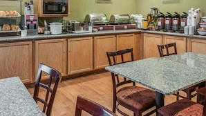A breakfast area with a microwave, toaster, and coffee maker. There are wooden cabinets and a granite countertop. - Quality Inn & Suites Farmington (Farmington)