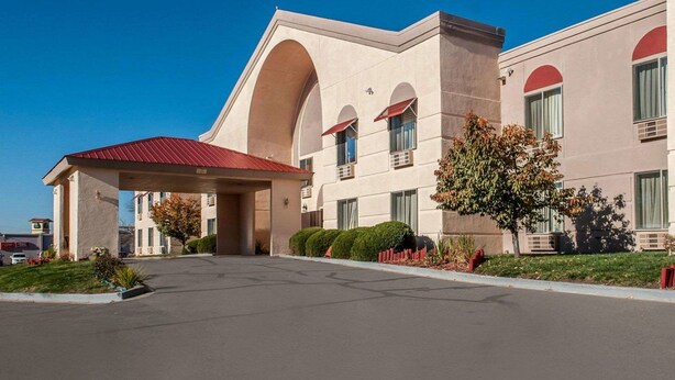 A hotel with a covered entrance, multiple windows, and a red roof. - Quality Inn & Suites Farmington (Farmington)