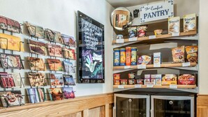 A cozy corner with a wooden cabinet, a refrigerator, and shelves stocked with snacks and a chalkboard menu. - Quality Inn & Suites Farmington (Farmington)