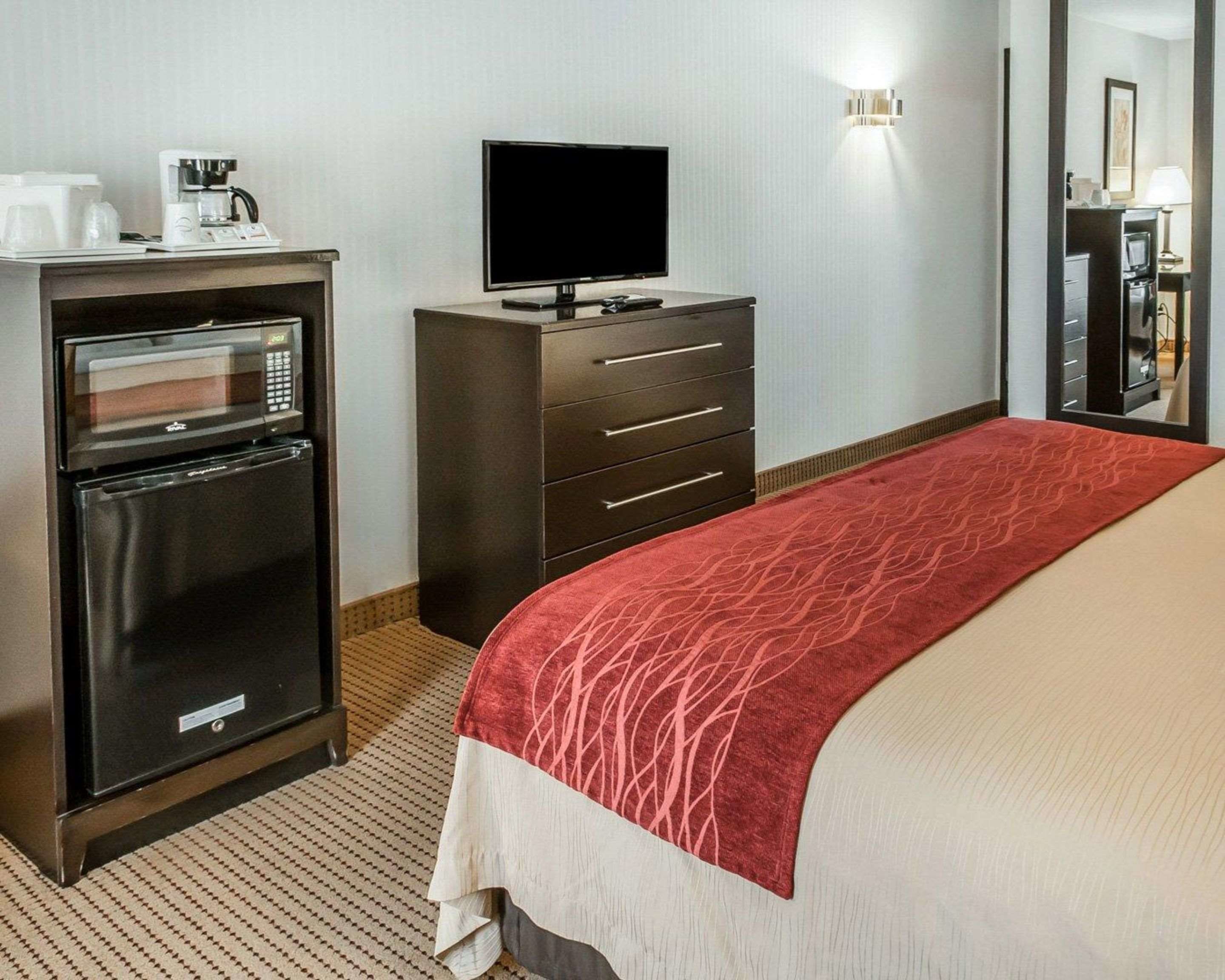 Une chambre d’hôtel équipée d’un lit, d’une télévision, d’un mini-bar, d’une machine à café et d’un four à micro-ondes.