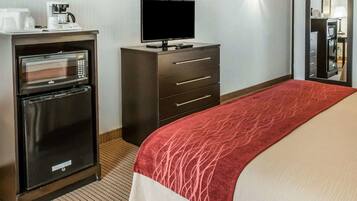 Una habitación de hotel con cama, televisor, minibar, cafetera y microondas.