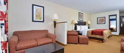 A hotel room with a sofa, a bed, a small table, and two lamps.