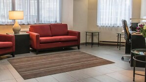 A modern living room with a red sofa, a small round table, a lamp, and a chair. - Comfort Inn Thunder Bay (Thunder Bay)