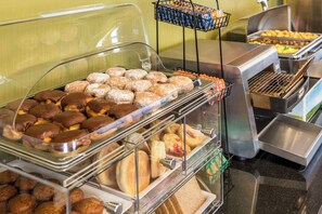 A buffet with various baked goods including donuts, muffins, and pastries.
