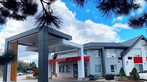 A modern building with a covered entrance, a red awning, and a parking area with a white car. - Comfort Inn Thunder Bay (Thunder Bay)