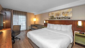 A hotel room with a large bed, a desk with a chair, a TV, and a painting on the wall. - Comfort Inn Thunder Bay (Thunder Bay)