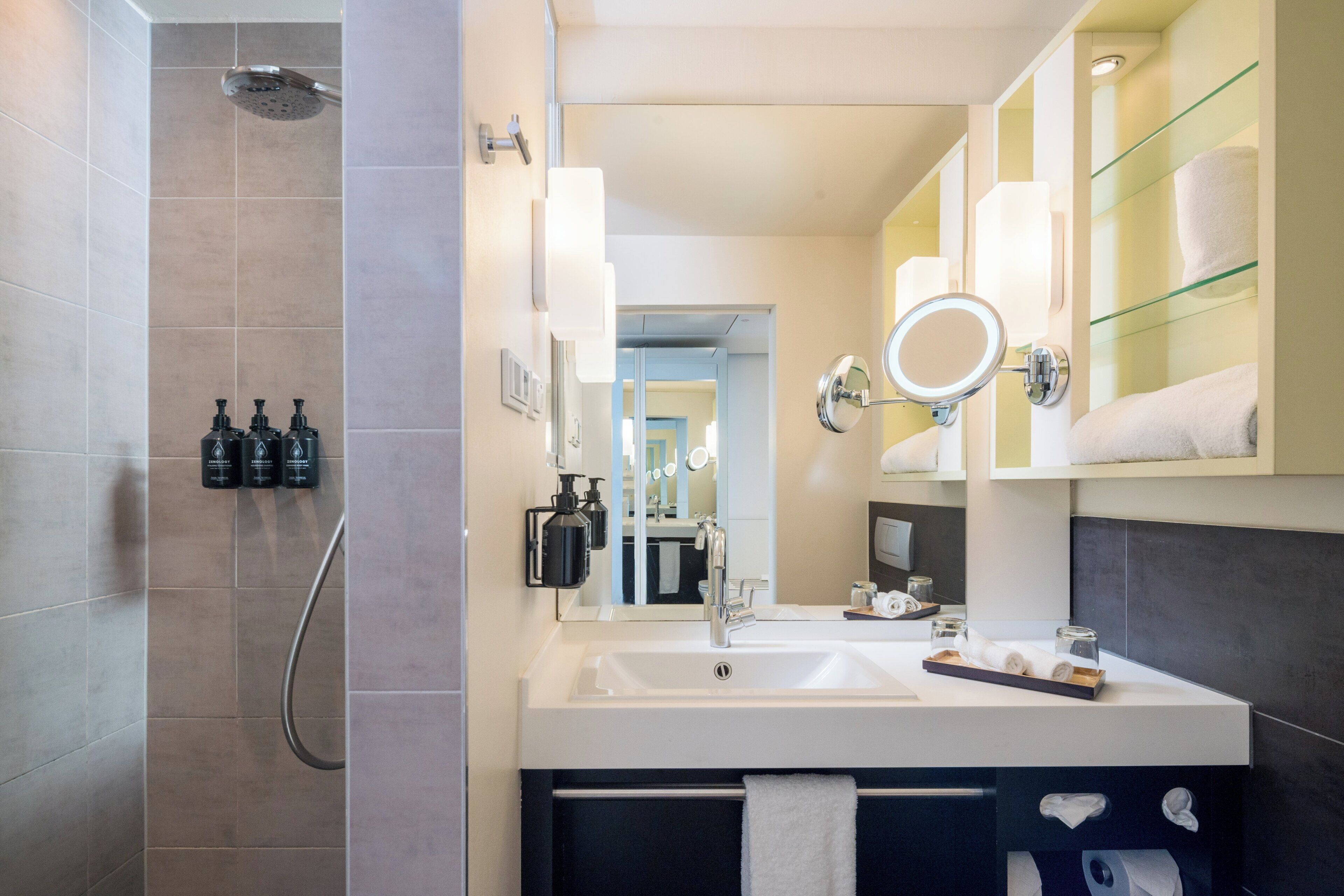 A modern bathroom with a shower, sink, and vanity mirror.