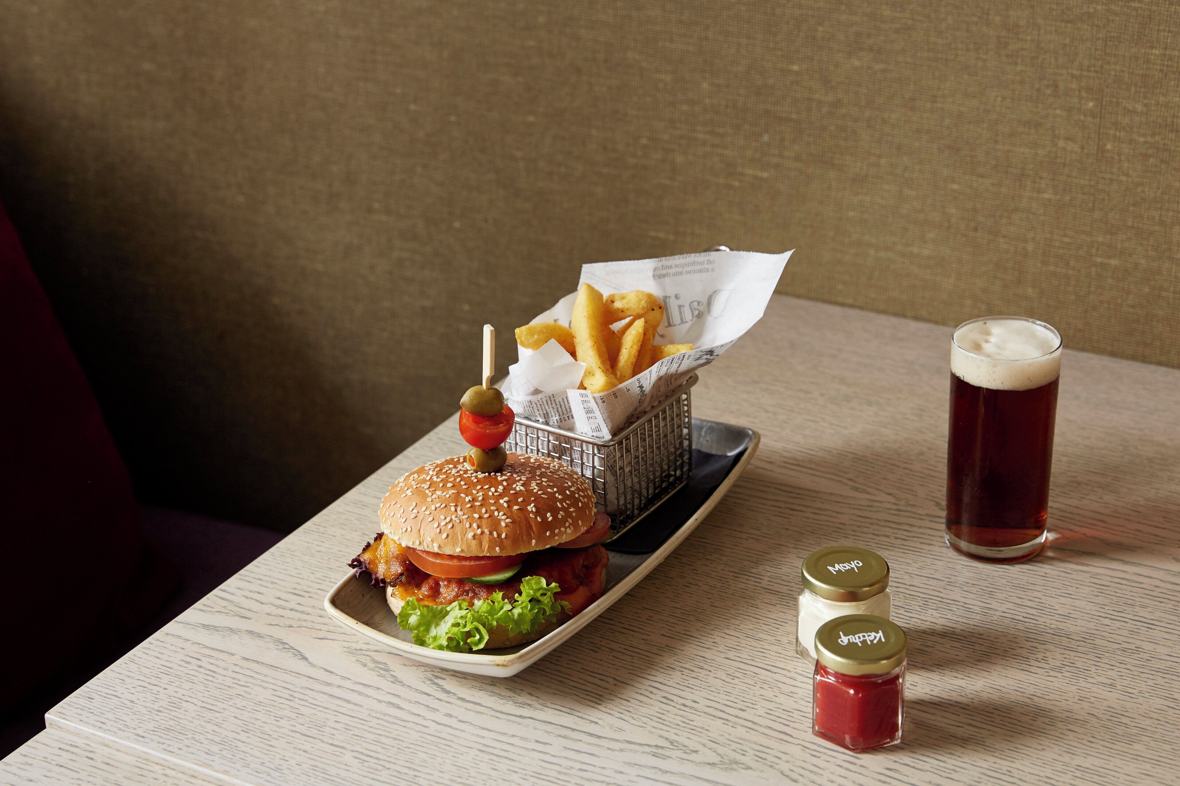 A meal consisting of a burger, fries, and a drink on a wooden table.