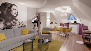 Een moderne woonkamer met een bank, fauteuils en een eettafel.