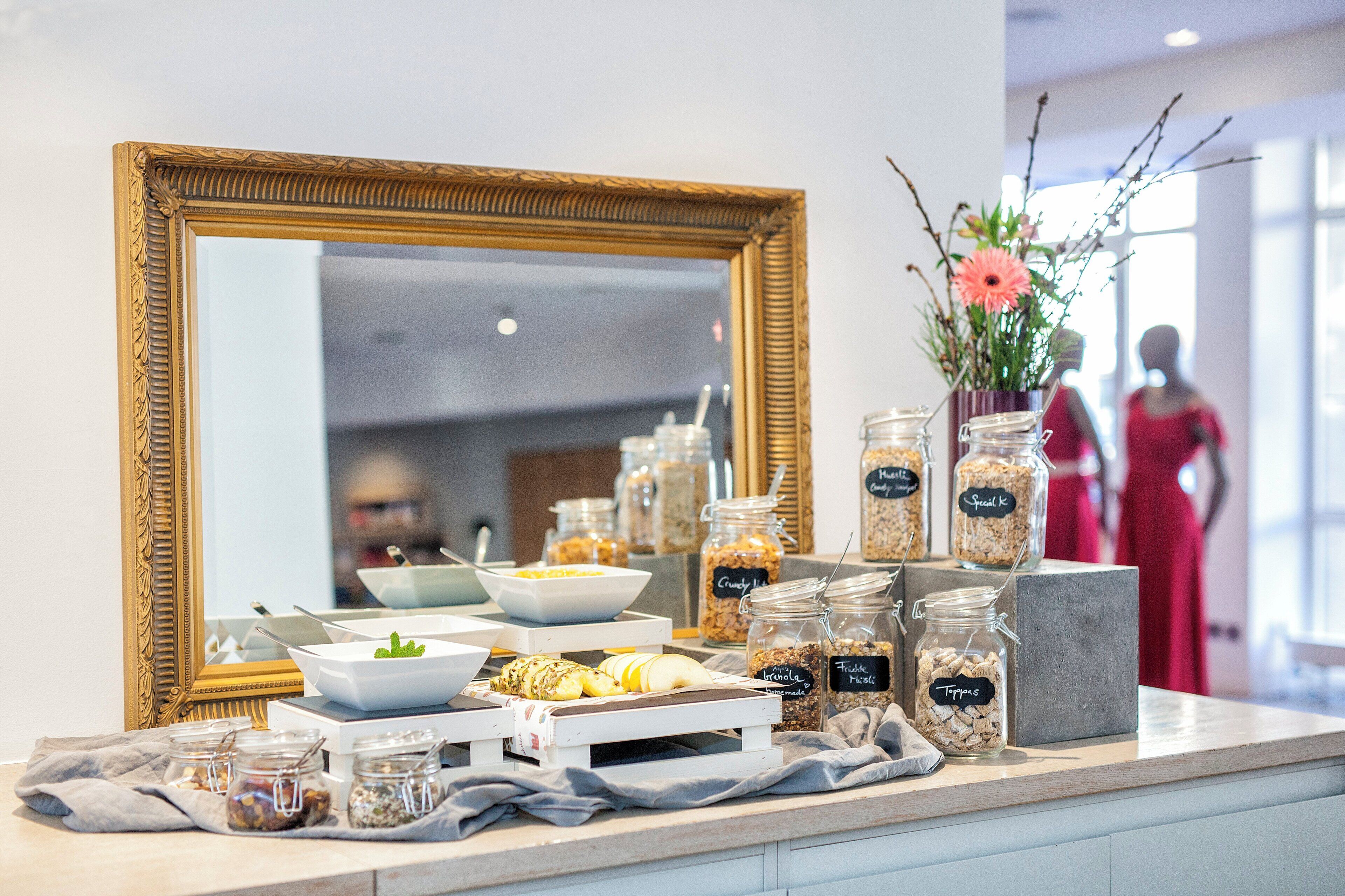 A buffet setup with various food items and a large mirror.