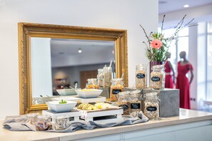 A buffet setup with various food items and a large mirror.