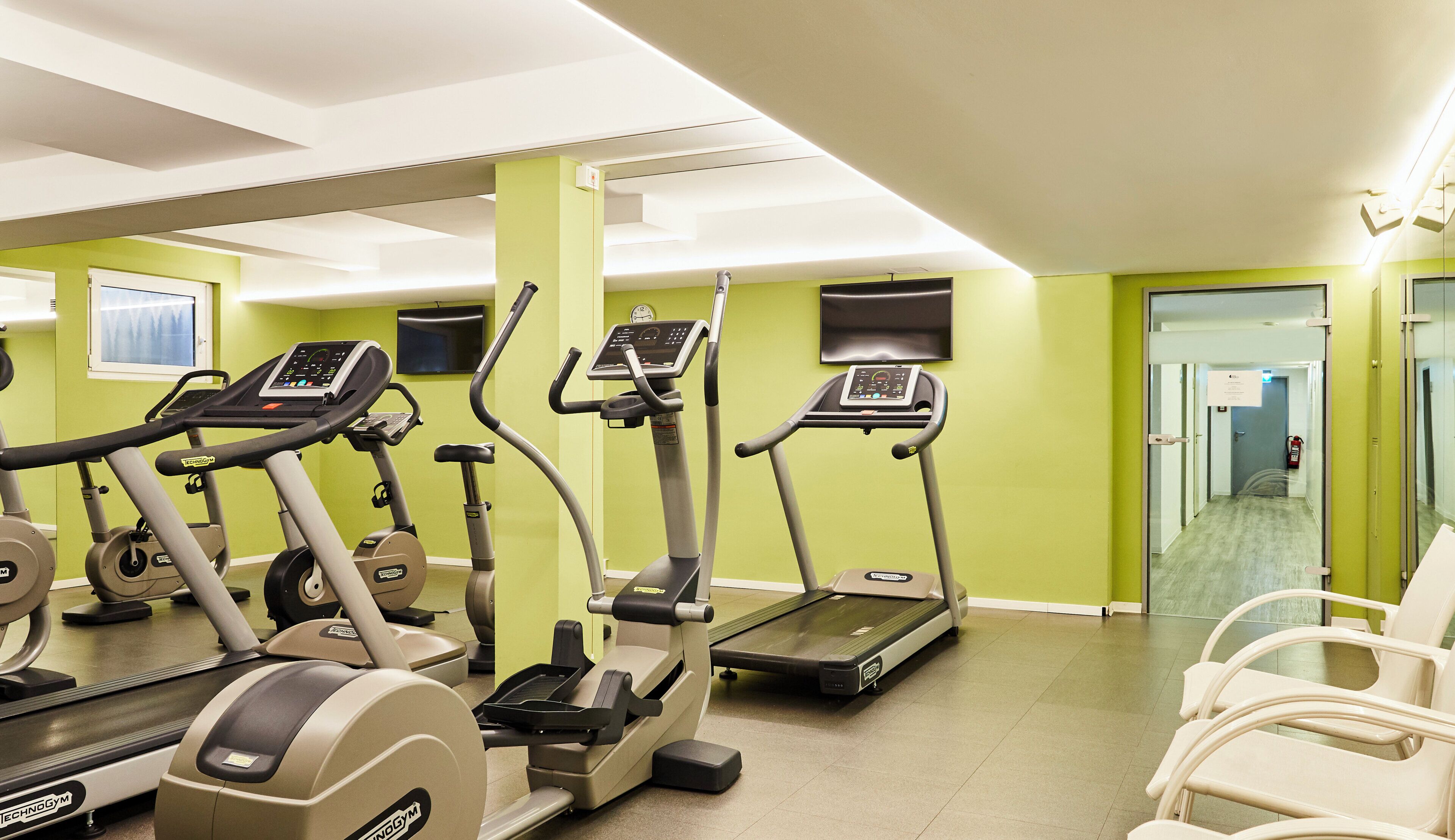 A fitness center with treadmills, stationary bikes, and exercise chairs.