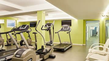 A fitness center with treadmills, stationary bikes, and exercise chairs.