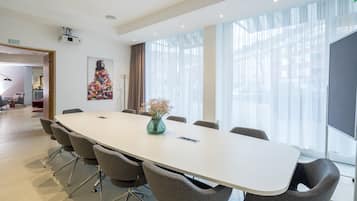 A conference room with a long table, six chairs, and a vase with flowers.