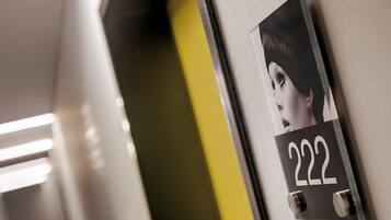 A close-up of a room number sign, 222, mounted on a wall with a partial view of a door and a light fixture.