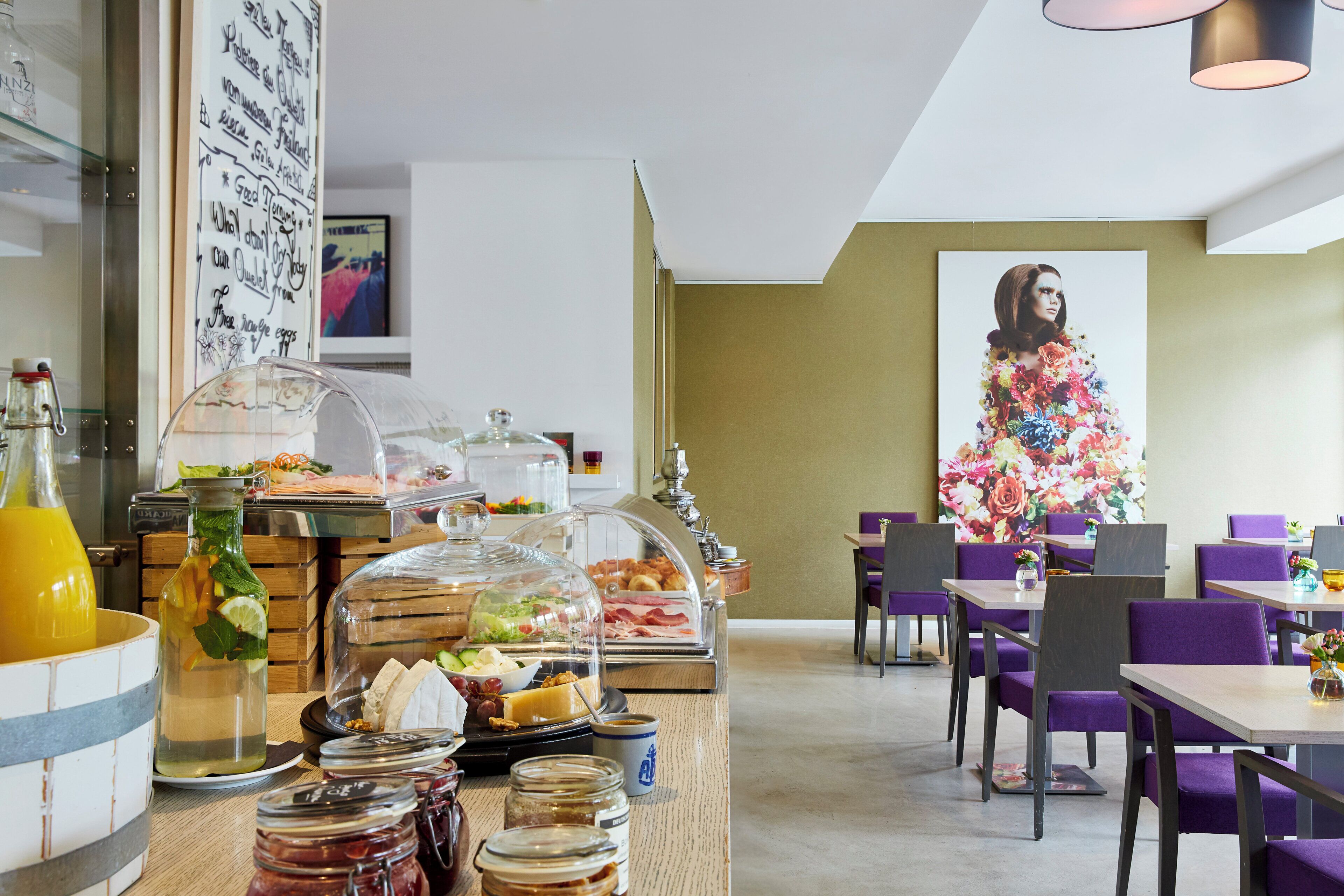 Un buffet de petit-déjeuner proposant une variété d’aliments et une grande œuvre d’art florale accrochée au mur.