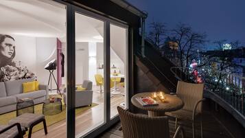 Un espacio habitable moderno con balcón, zona de comedor y vista a la ciudad de noche.