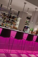 A bar area with multiple liquor bottles, a bar counter, and several chairs.