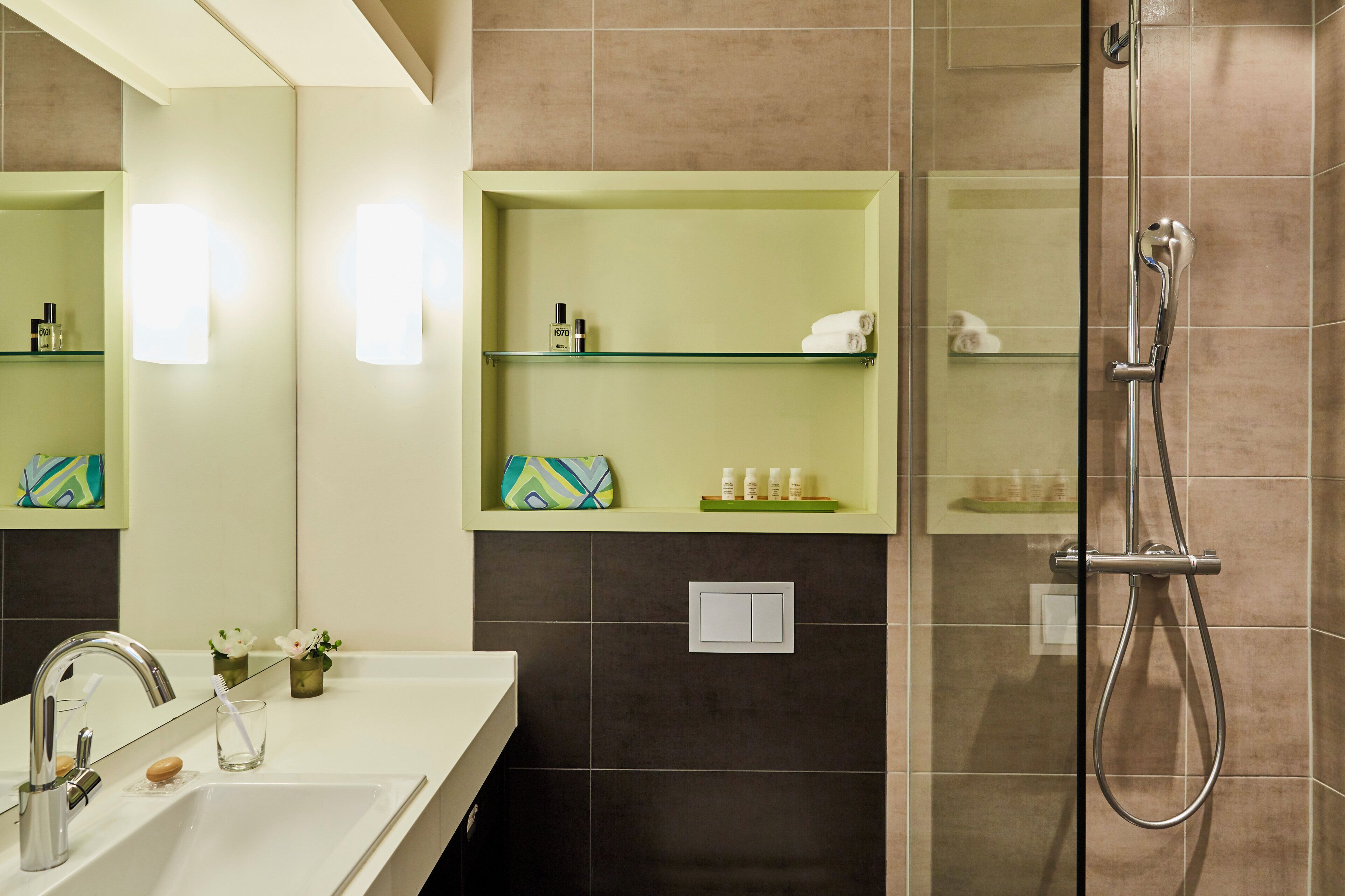 Une salle de bain équipée d’un lavabo, d’un miroir, d’étagères contenant des articles de toilette et d’une douche.