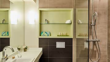 Une salle de bain équipée d’un lavabo, d’un miroir, d’étagères contenant des articles de toilette et d’une douche.