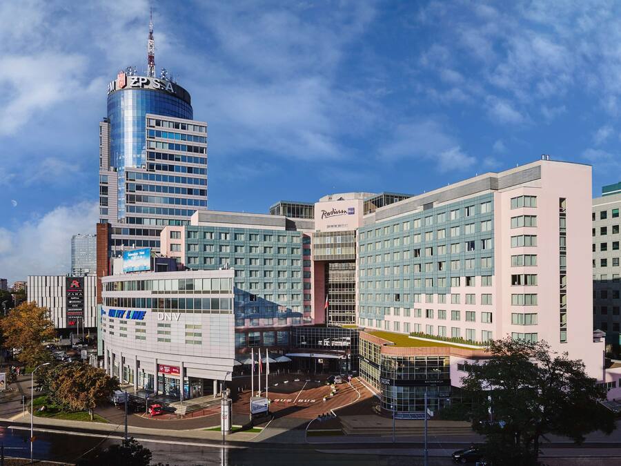 Un hotel moderno con un edificio cilíndrico destacado, un amplio frente de vidrio y un área de entrada espaciosa.