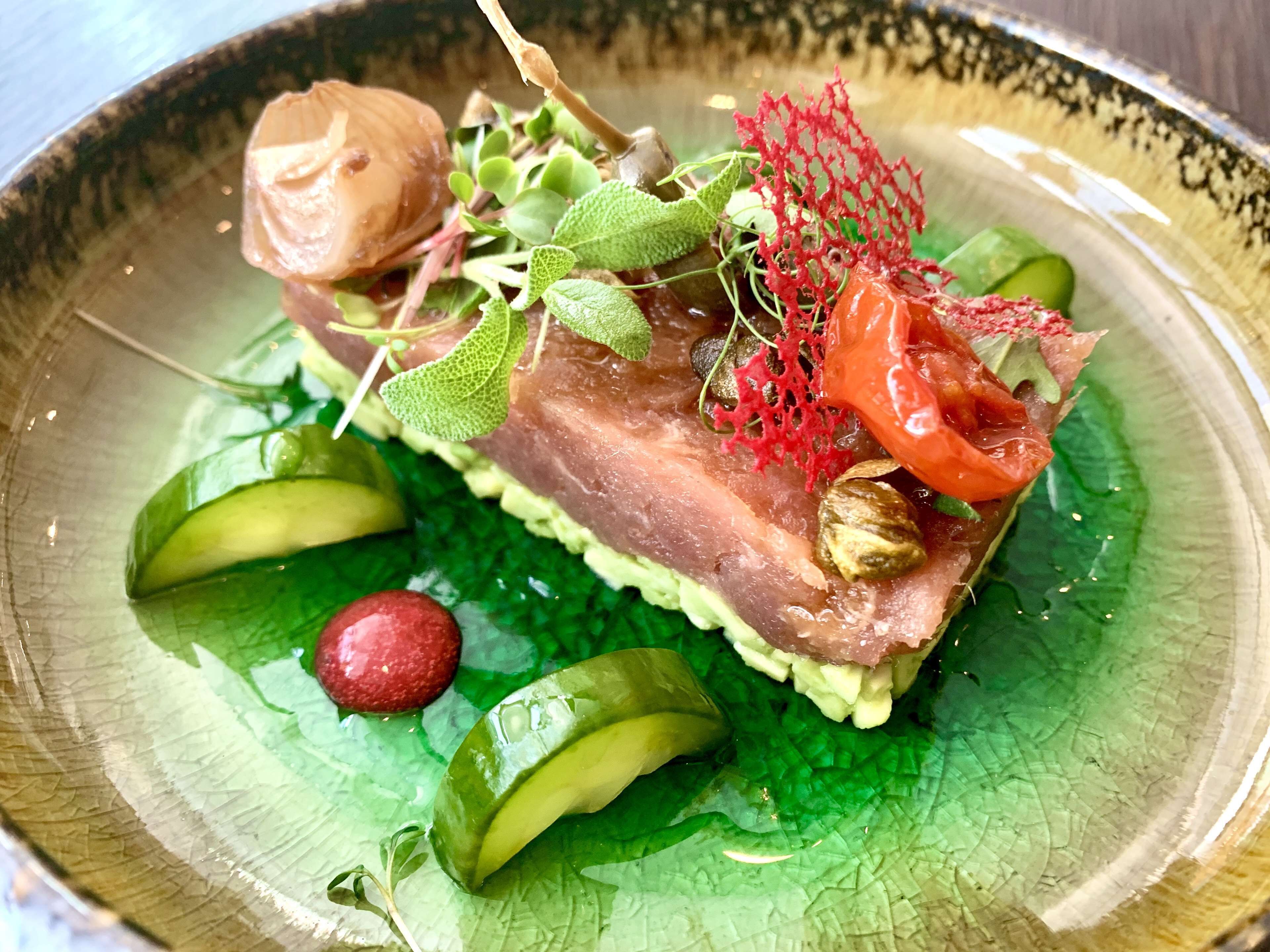 A dish with various ingredients on a green leaf base.