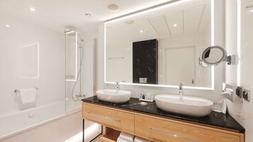 A modern bathroom with two sinks, a large mirror, and a glass-enclosed shower.
