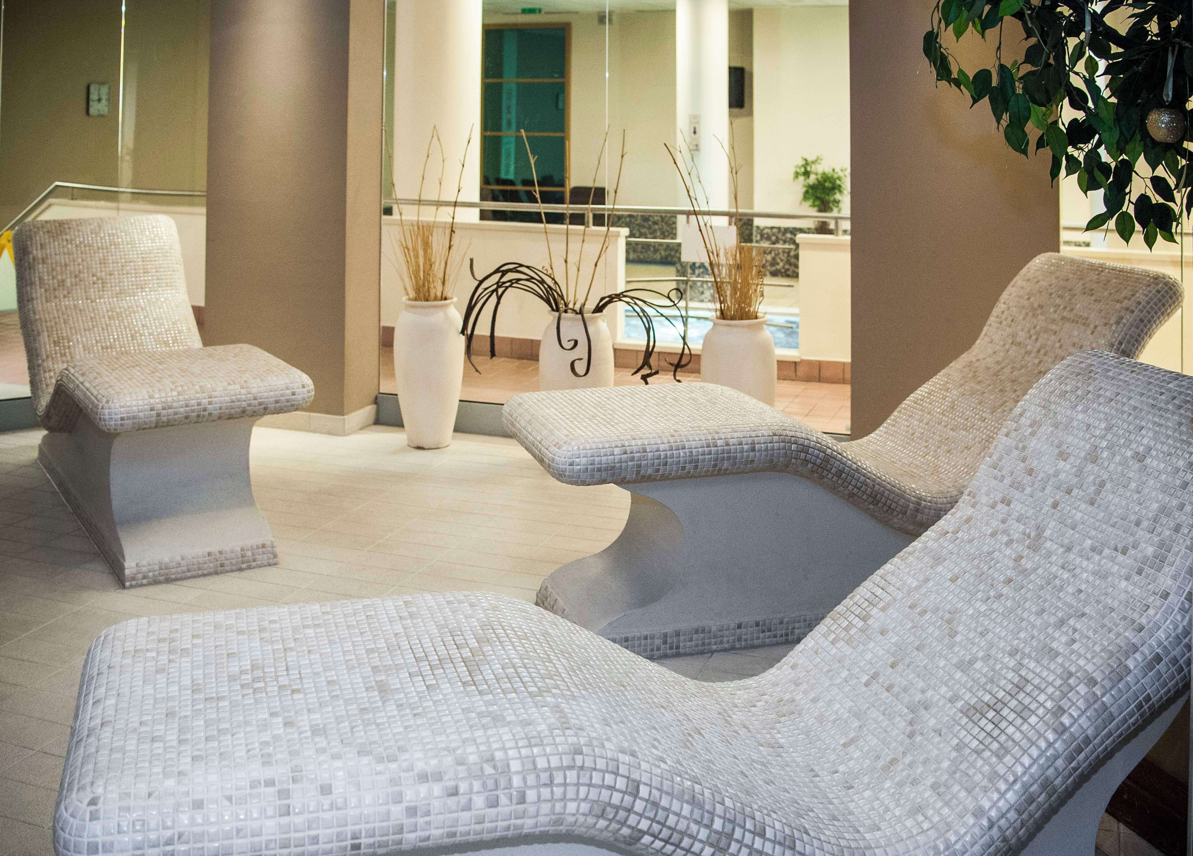 A spa area with three lounge chairs and a decorative plant arrangement.