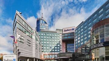 Et Radisson Blu hotel med en moderne glasfacade, en fremtrædende ZPSA-bygning i baggrunden og en Europa restaurant & café.