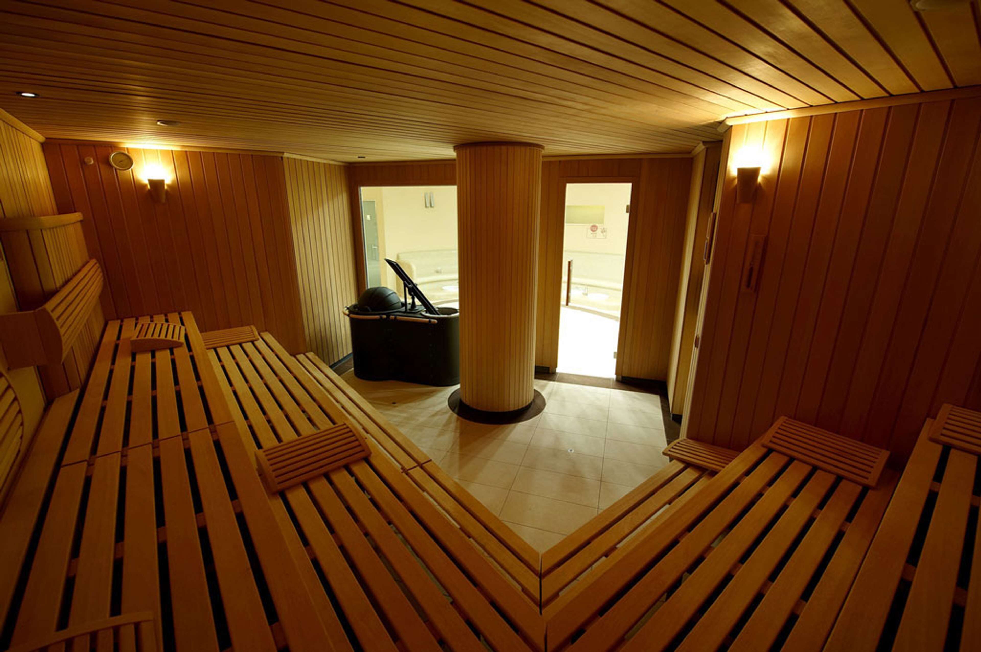 A sauna room with wooden benches and a central pillar.