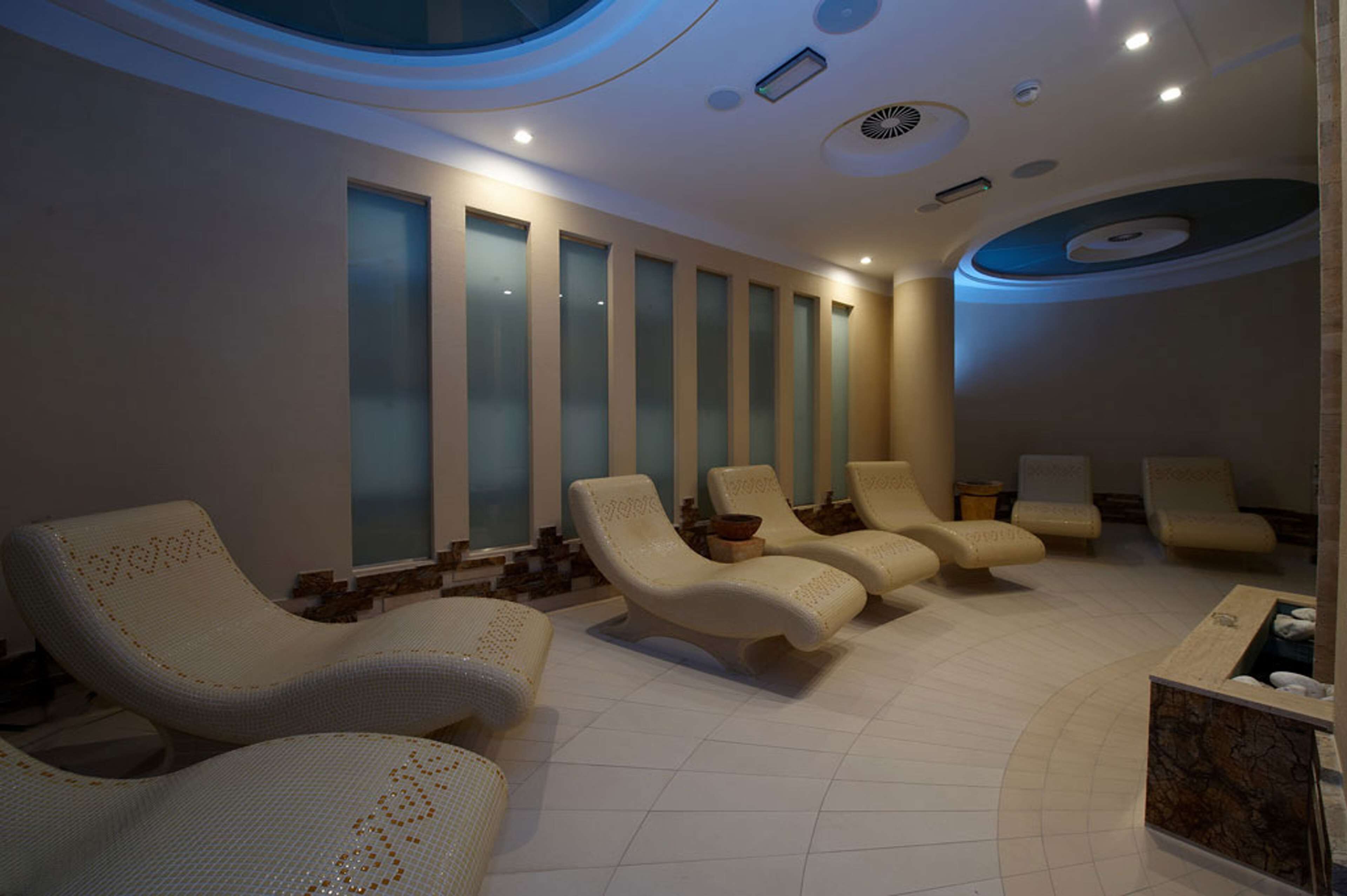 Un cuarto de spa con sillones reclinables, una camilla de masaje y un ventanal grande.